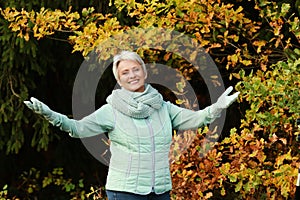 Happy senior woman spread her arms in nature