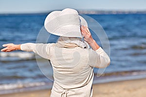 Happy senior woman in sun hat on summer beach