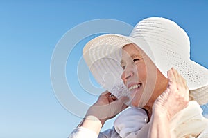 Happy senior woman in sun hat on summer beach