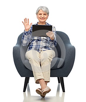 happy senior woman with tablet pc sitting in chair