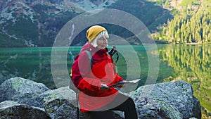 Happy senior woman tourist search a map in mountains at Morskie Oko lake near Zakopane, Tatra Mountains, Poland. Family