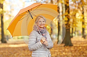 Happy senior woman with umbrella at autumn park
