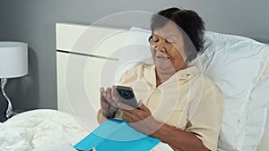 Happy senior woman using mobile phone in bed