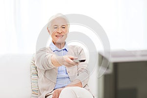 Happy senior woman watching tv at home