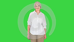 Happy Senior Woman in White Shirt Smiling to Camera on a Green Screen, Chroma Key.