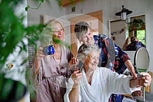 Happy senior women friends in bathrobes having fun indoors in bathroom, selfcare concept.