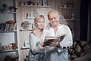 Happy seniors couple embrace and read book;