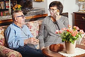 Happy seniors couple sitting on the couch while woman talking on the phone.