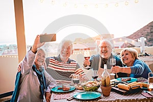 Happy seniors friends taking selfie with mobile smartphone camera at barbecue dinner