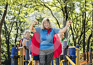Happy seniors wearing superhero costumes at a playground