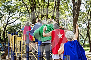 Happy seniors wearing superhero costumes at a playground