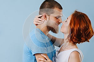 Happy couple in love kissing at home over blue background.