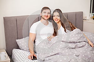 Happy sensual young couple lying in bed together.