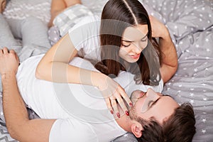 Happy sensual young couple lying in bed together.