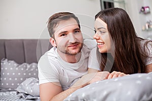 Happy sensual young couple lying in bed together.