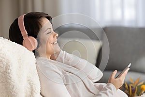 Happy serene young pregnant woman in headphones enjoying relaxing music