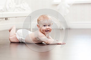 Happy seven month old baby girl crawling on a hardwood floor