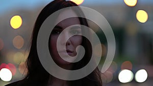 Happy sexual brunette woman in big city after sunset, night lights in background, closeup