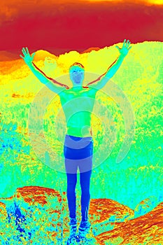 Happy shirtless man with raised arms on peak. Wild landscape bellow. Amazing thermography photo of hilly landscape.