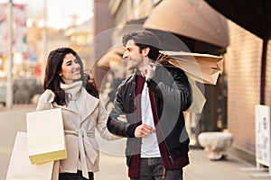 Happy shopaholics walking with shopping bags after making purchases