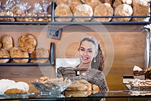 Happy shopgirl working in bakery with bread