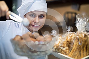 Happy shopgirl working with different pastry