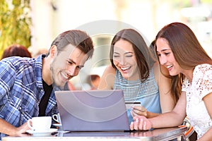 Happy shoppers paying online with credit card in a bar