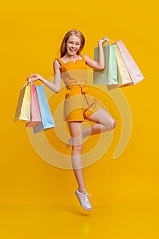 Happy Shopping. Overjoyed Girl Jumping In Air With Shopper Bags