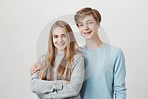 Happy siblings care for each other. Portrait of brother and sister with fair hair and braces, hugging and smiling