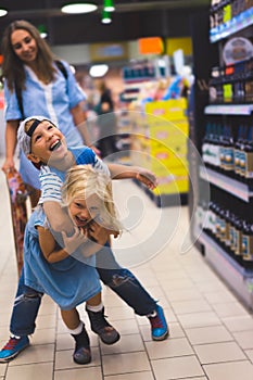 happy siblings having fun in supermarket mother