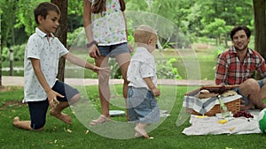 Happy siblings playing in park. Young family having picnic outdoors.