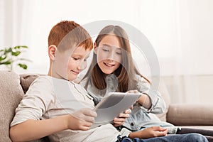 Happy siblings playing with pc tablet together