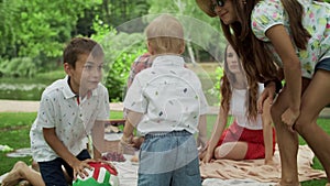 Happy siblings playing together in forest. Smiling family having picnic outdoors