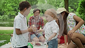 Happy siblings playing together in forest. Smiling family having picnic outdoors