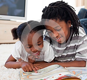 Happy siblings reading lying on the floor