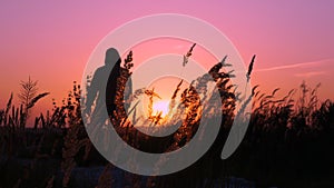 Happy silhouette of a man on a mountain at an orange sunrise or sunset. Sad or pensive man on the mountain