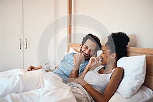 Happy, silly and goofy couple bonding in bed, sharing intimate relationship joke and moment. Young interracial husband