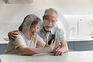 Happy sincere mature old family couple using cellphone.