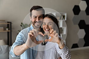 Happy sincere young family couple showing keys to camera.