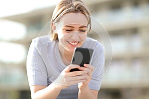 Happy single teen using smart phone in the street