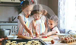 Happy sisters children girls bake cookies, knead dough, play wit