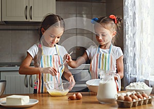 Happy sisters children girls bake cookies, knead dough, play wit