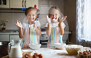 Happy sisters children girls bake cookies, knead dough, play wit