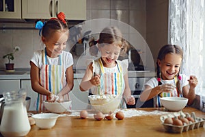 Happy sisters children girls bake cookies, knead dough, play wit