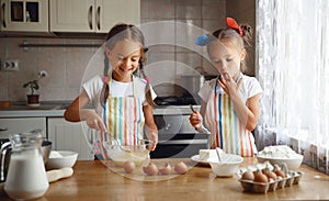 Happy sisters children girls bake cookies, knead dough, play wit