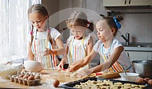 Happy sisters children girls bake cookies, knead dough, play wit