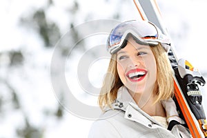 Happy skier holding skis looking at side