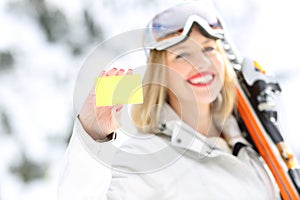 Happy skier showing a card in a slope