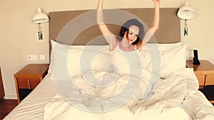 Happy sleepy young woman waking up lying in bed. Positive pretty girl stretching enjoying early good morning in cozy