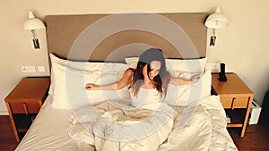 Happy sleepy young woman waking up lying in bed. Positive pretty girl stretching enjoying early good morning in cozy